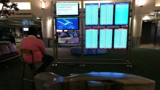 Un voyageur branche sa PS4 sur un moniteur d'aéroport